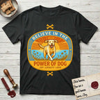 Believe in the Power of Dog Yellow Lab T-Shirt flat lay in Black, featuring a vintage oval badge with a haloed Yellow Lab running through a field of wildflowers and the words Joy, Loyalty, Love.