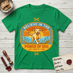 Believe in the Power of Dog Yellow Lab T-Shirt flat lay in Irish Green, featuring a vintage oval badge with a haloed Yellow Lab running through a field of wildflowers and the words Joy, Loyalty, Love.