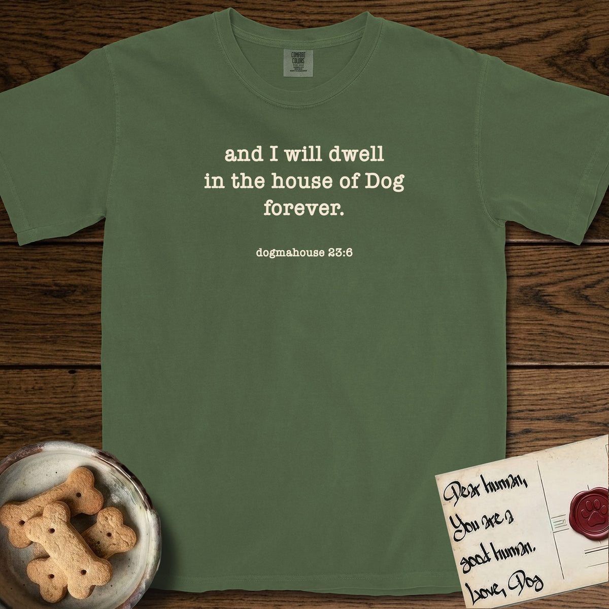 And I Will Dwell T-Shirt flat lay in Moss, featuring Small centered typewriter-type text reading and I will dwell in the house of Dog forever, with the citation dogmahouse 23:6 beneath it.