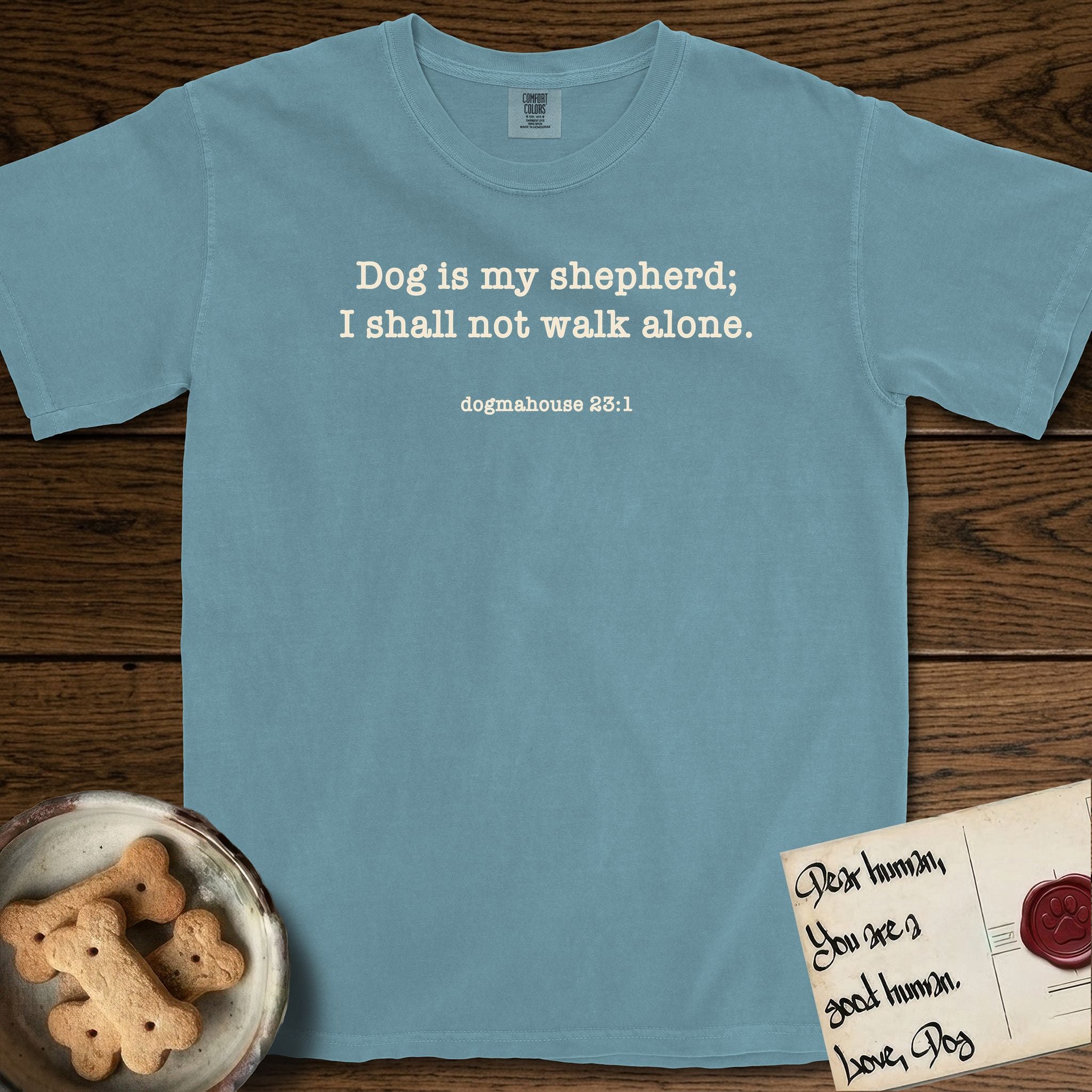 Dog is My Shepherd T-Shirt flat lay in Ice Blue, featuring Small centered typewriter-type text reading Dog is my shepherd; I shall not walk alone, with the citation dogmahouse 23:1 beneath it.