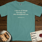 I Can Do All Things T-Shirt flat lay in Blue Spruce, featuring Small centered typewriter-type text reading i can do all things through Dog, who strengthens me, with the citation dogmahouse 4:13 beneath it.