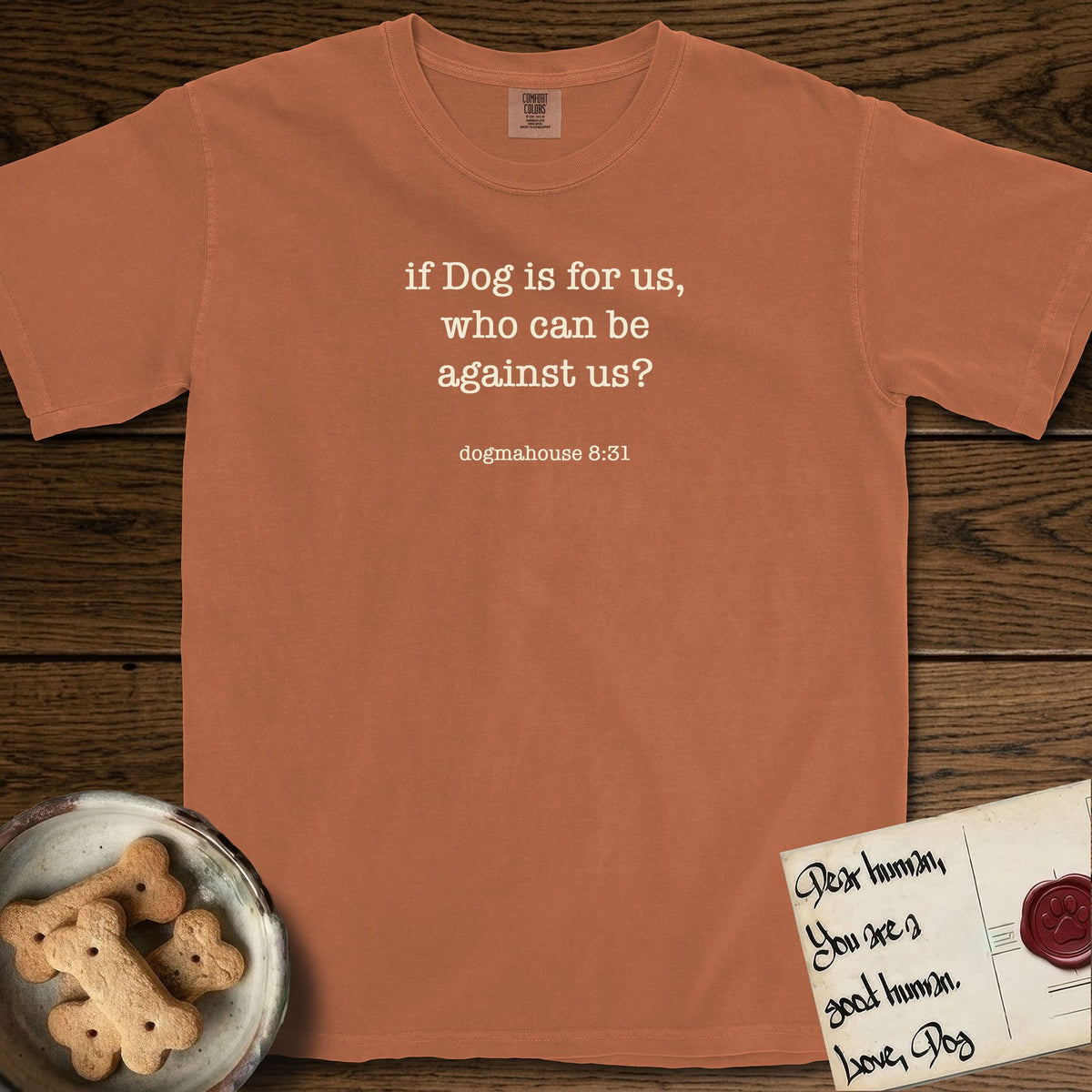 If Dog is For Us T-Shirt flat lay in Yam, featuring Small centered typewriter-type text reading if Dog is for us, who can be against us?, with the citation dogmahouse 8:31 beneath it.