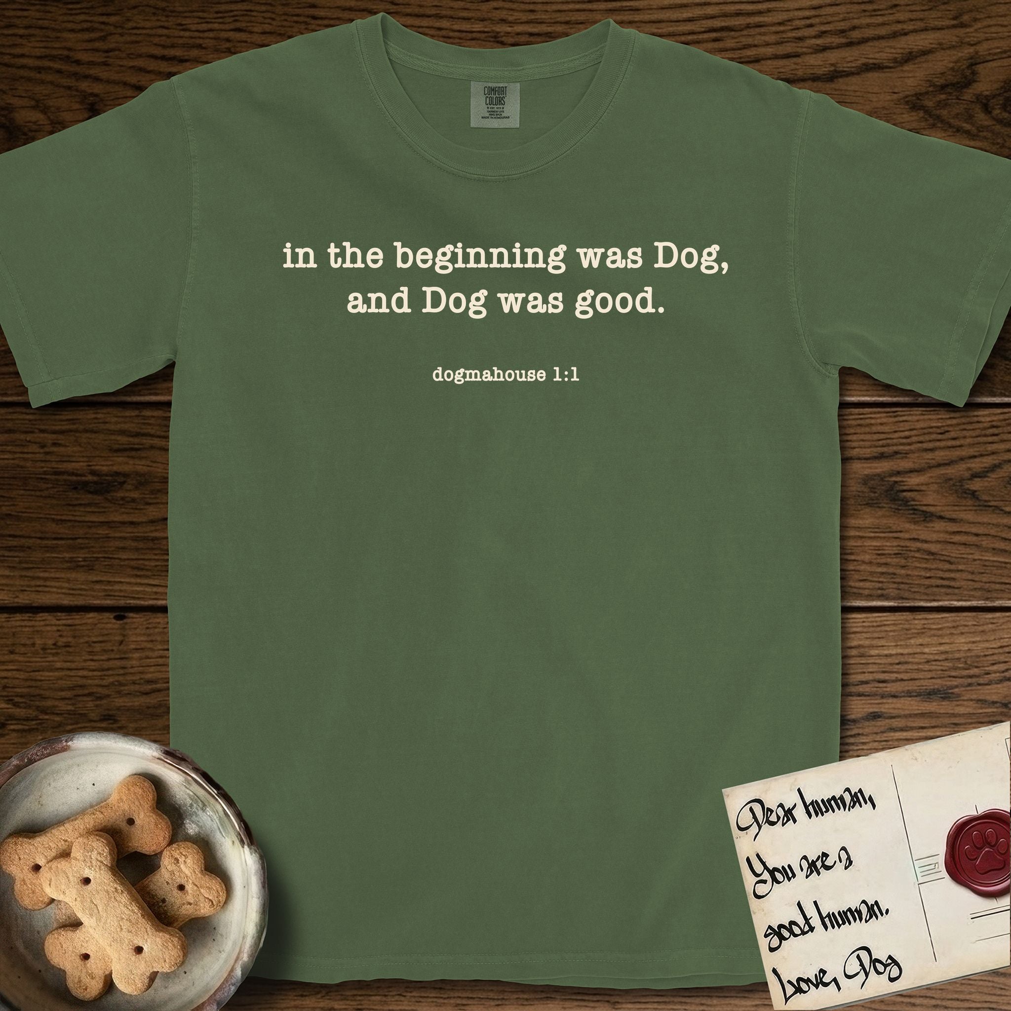 In the Beginning T-Shirt flat lay in Moss, featuring Small centered typewriter-type text reading in the beginning was Dog, and Dog was good, with the citation dogmahouse 1:1 beneath it.