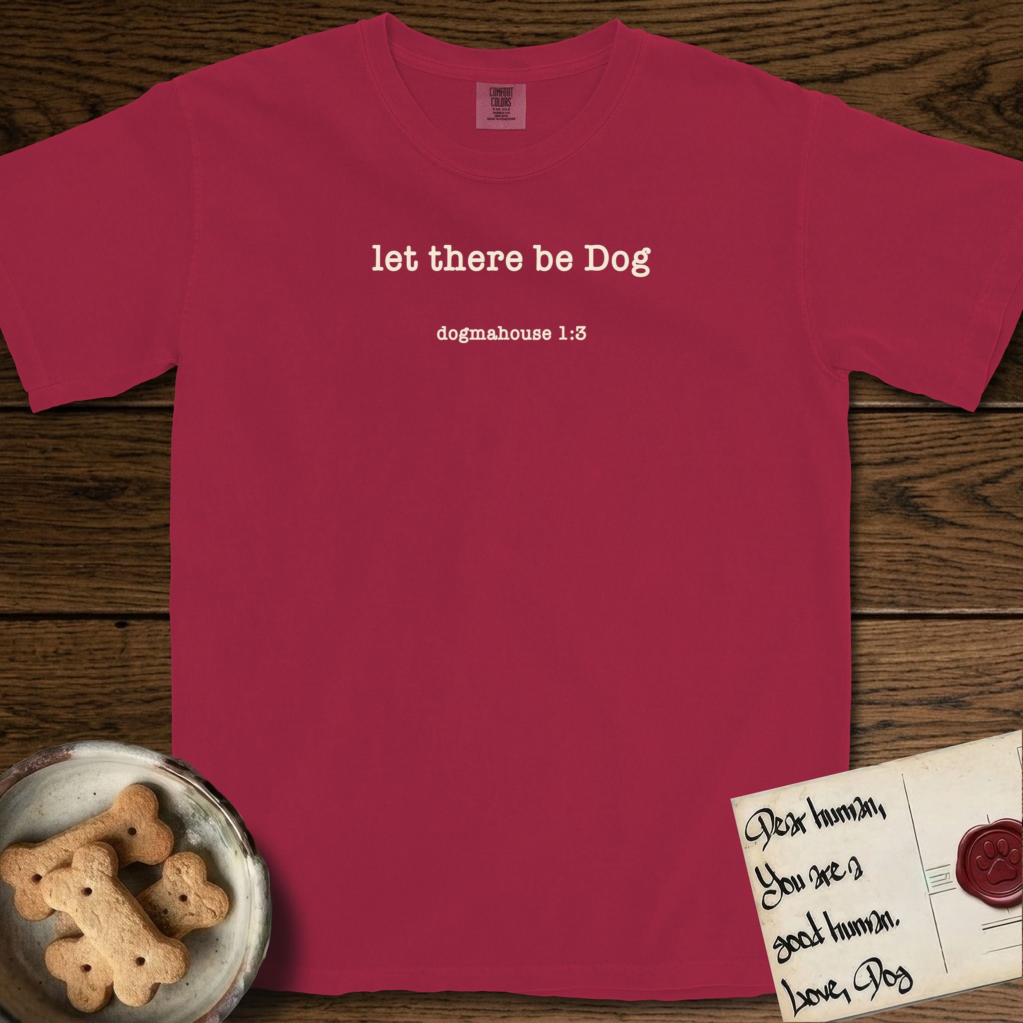 Let There Be Dog T-Shirt flat lay in Chili, featuring Small centered typewriter-type text reading let there be Dog, with the citation dogmahouse 1:3 beneath it.