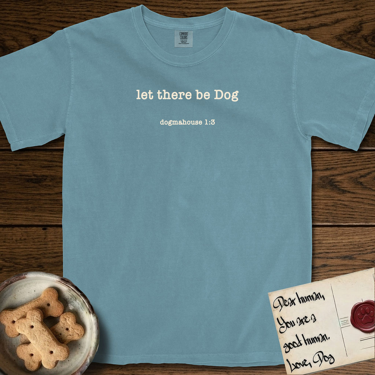 Let There Be Dog T-Shirt flat lay in Ice Blue, featuring Small centered typewriter-type text reading let there be Dog, with the citation dogmahouse 1:3 beneath it.