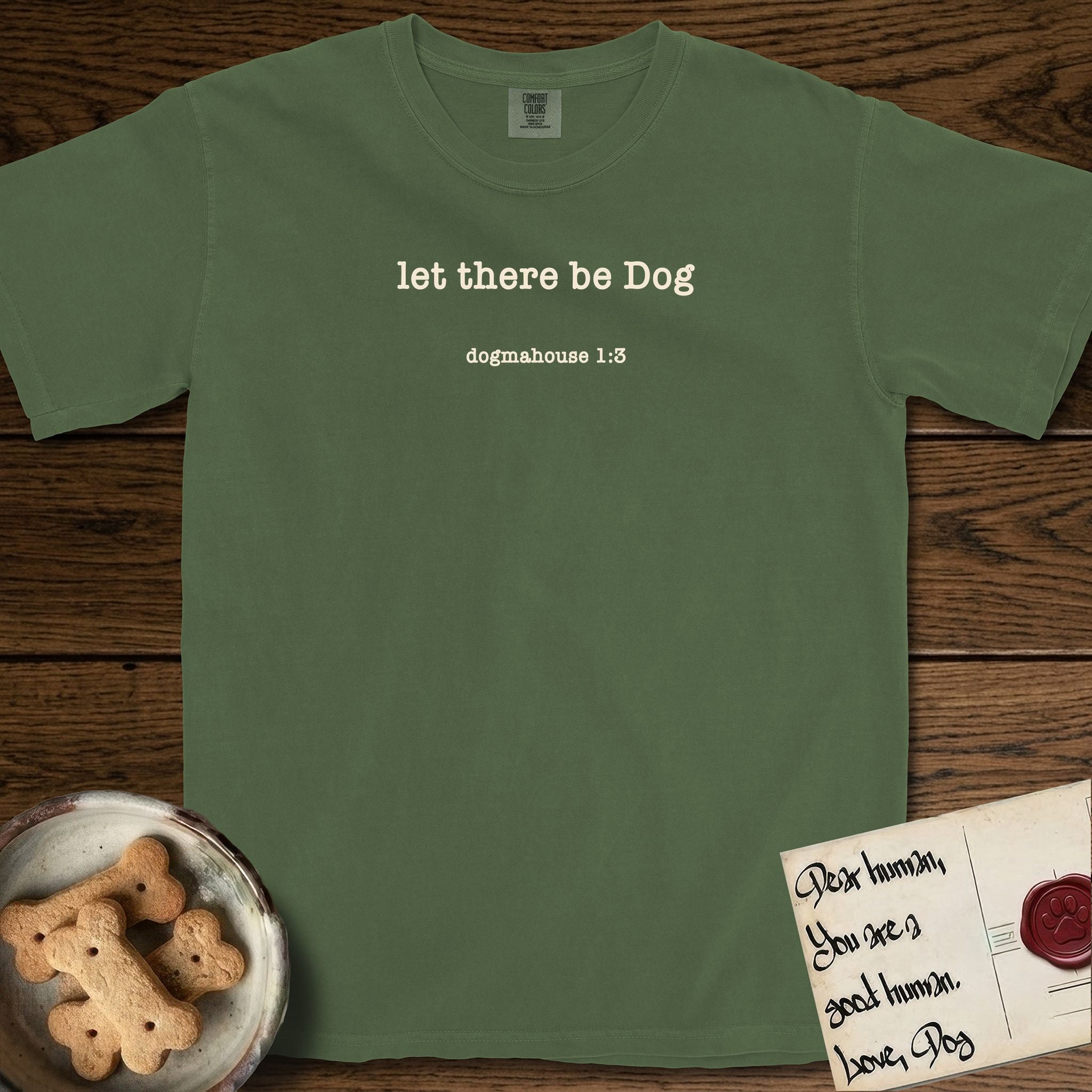 Let There Be Dog T-Shirt flat lay in Moss, featuring Small centered typewriter-type text reading let there be Dog, with the citation dogmahouse 1:3 beneath it.