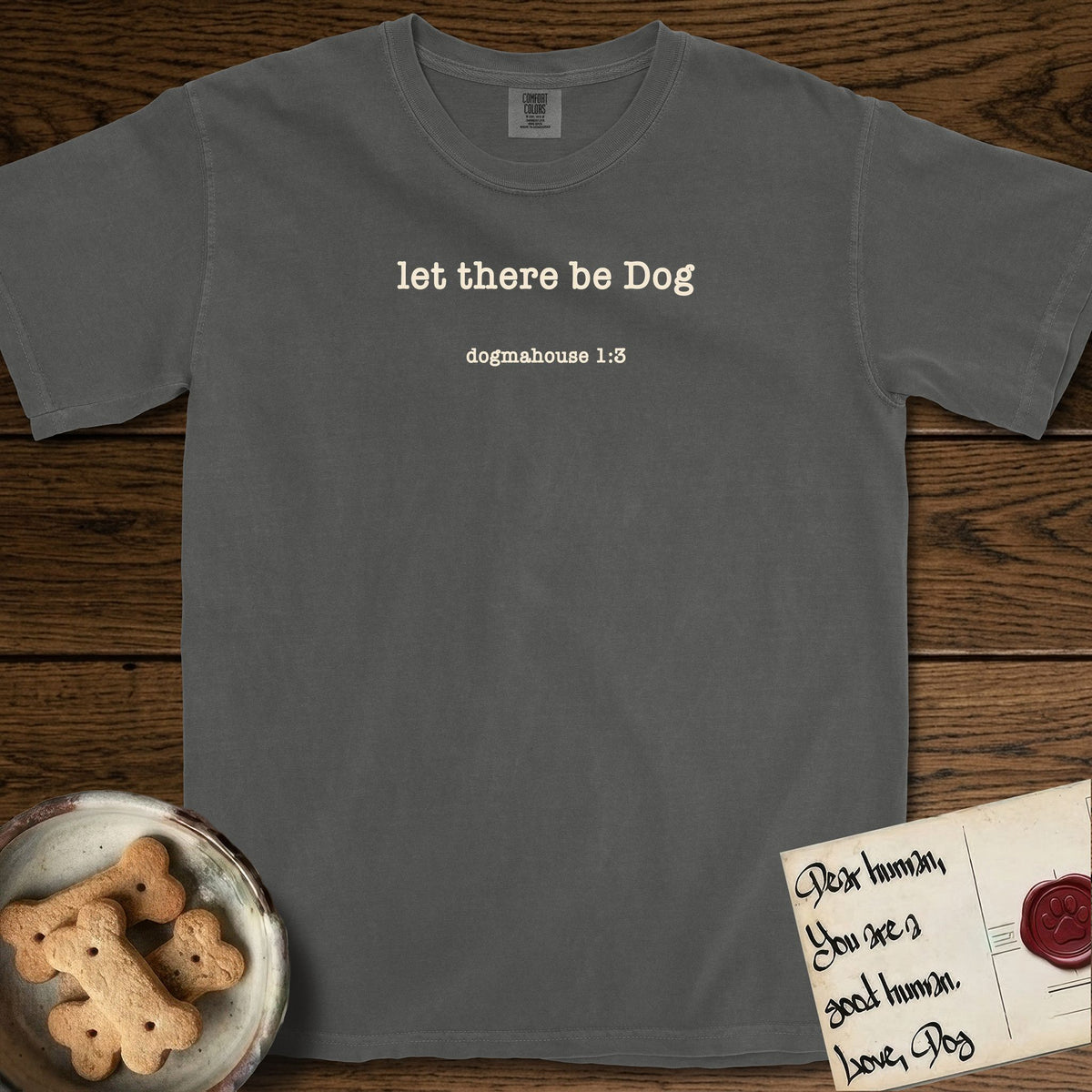 Let There Be Dog T-Shirt flat lay in Pepper, featuring Small centered typewriter-type text reading let there be Dog, with the citation dogmahouse 1:3 beneath it.