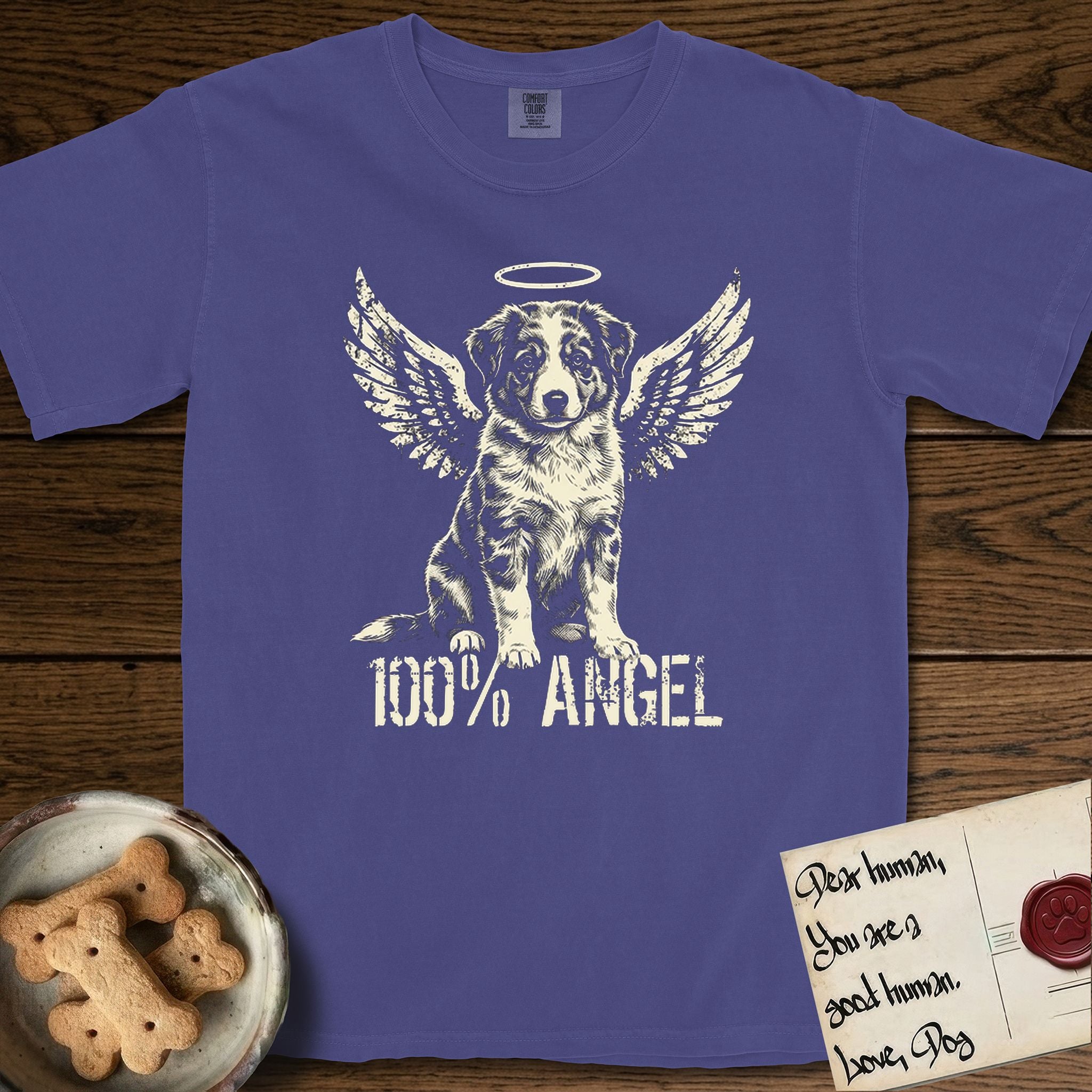 Australian Shepherd T-Shirt flat lay in Grape, featuring Distressed cream one-color screen-print of a blue merle Australian Shepherd puppy as an angel, wings raised and a halo above, with 100% ANGEL lettering across the bottom.