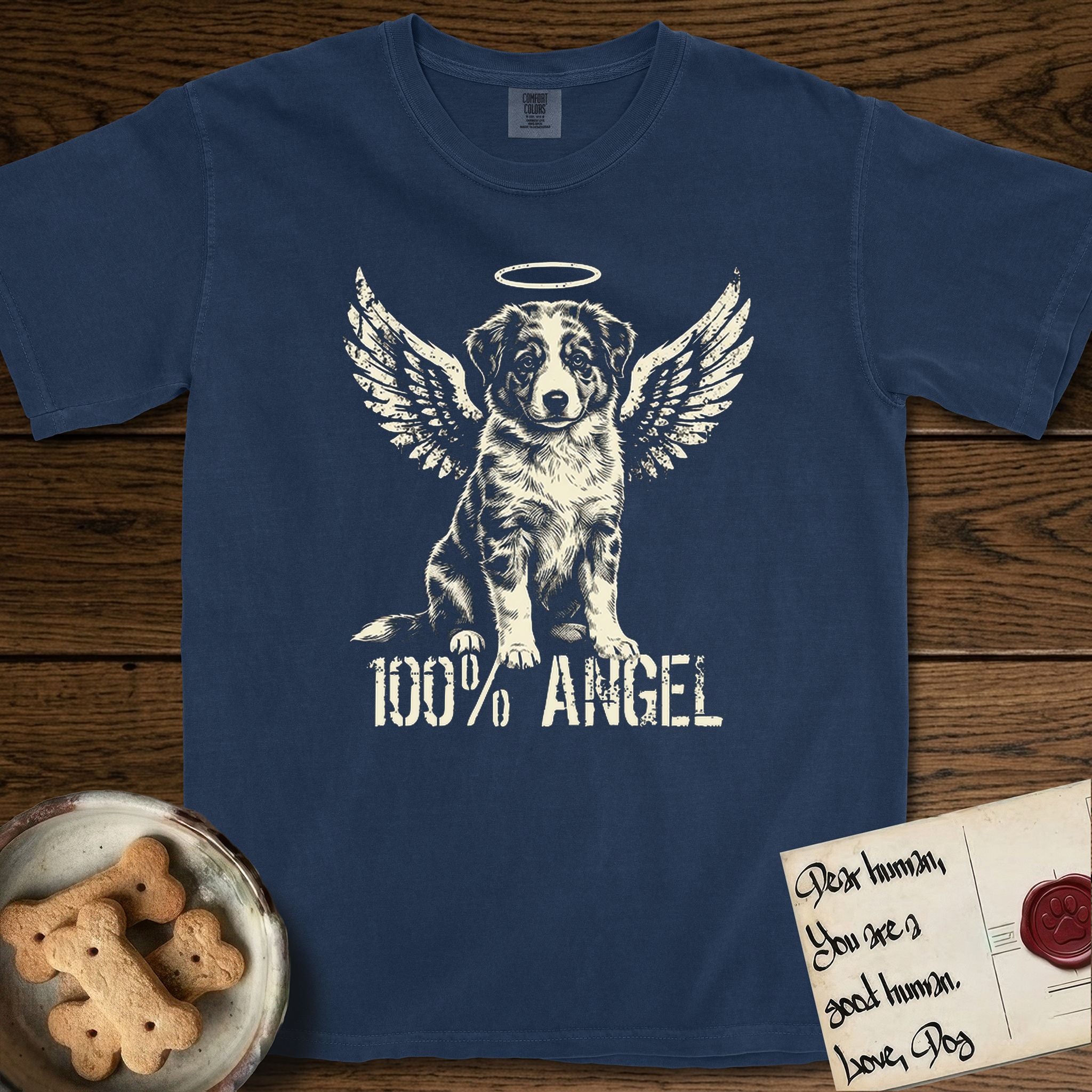 Australian Shepherd T-Shirt flat lay in True Navy, featuring Distressed cream one-color screen-print of a blue merle Australian Shepherd puppy as an angel, wings raised and a halo above, with 100% ANGEL lettering across the bottom.