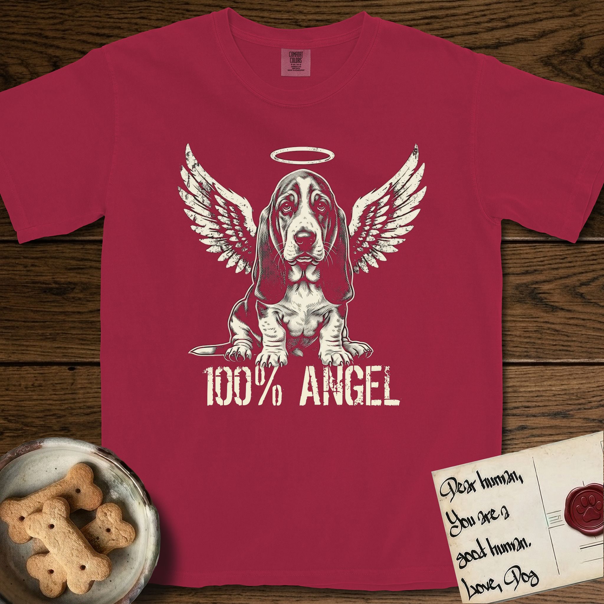 Basset Hound T-Shirt flat lay in Chili, featuring Distressed cream one-color screen-print of a Basset Hound puppy as an angel, long ears draping forward, wings spread and a halo above, with 100% ANGEL lettering across the bottom.