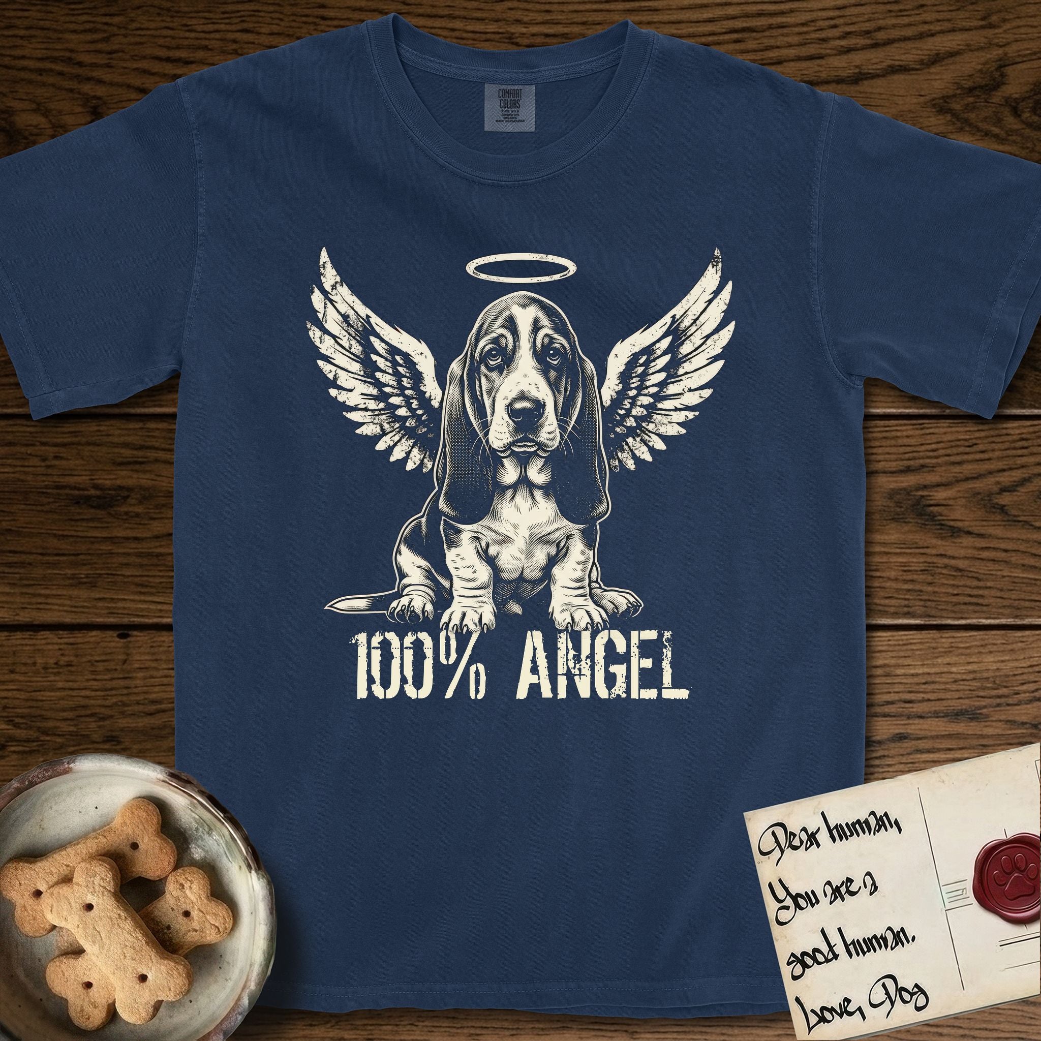 Basset Hound T-Shirt flat lay in True Navy, featuring Distressed cream one-color screen-print of a Basset Hound puppy as an angel, long ears draping forward, wings spread and a halo above, with 100% ANGEL lettering across the bottom.