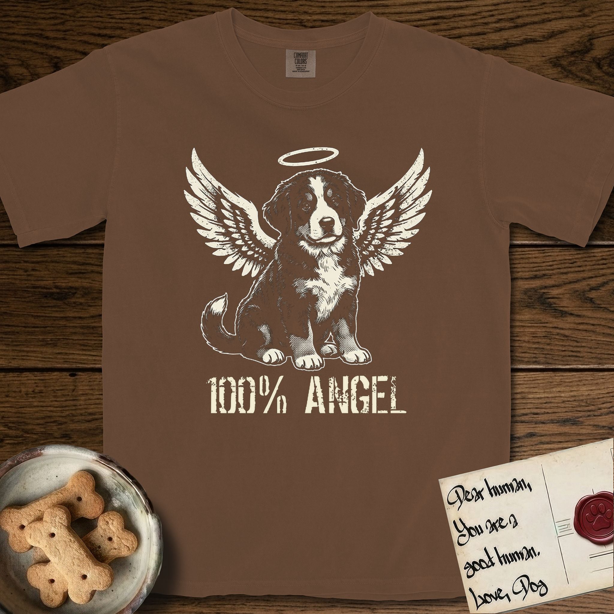 Bernese Mountain Dog T-Shirt flat lay in Espresso, featuring Distressed cream one-color screen-print of a Bernese Mountain Dog puppy as an angel, three-quarter sitting pose with bushy tail curled, wings spread and a halo above, with 100% ANGEL lettering across the bottom.