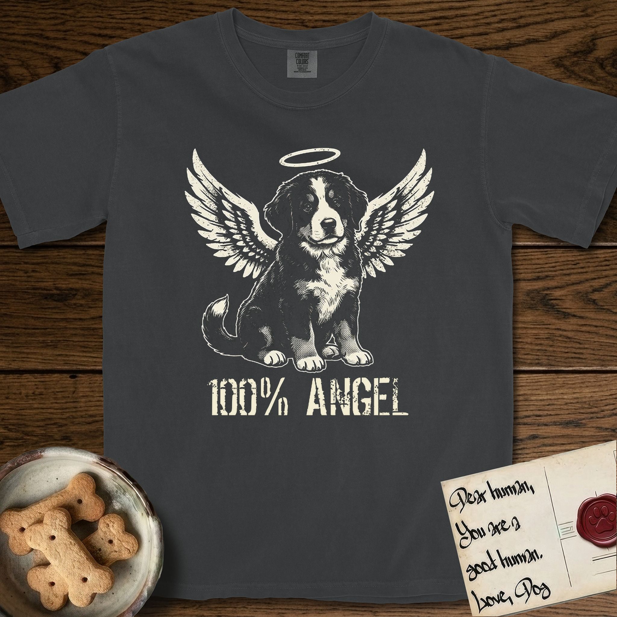 Bernese Mountain Dog T-Shirt flat lay in Graphite, featuring Distressed cream one-color screen-print of a Bernese Mountain Dog puppy as an angel, three-quarter sitting pose with bushy tail curled, wings spread and a halo above, with 100% ANGEL lettering across the bottom.