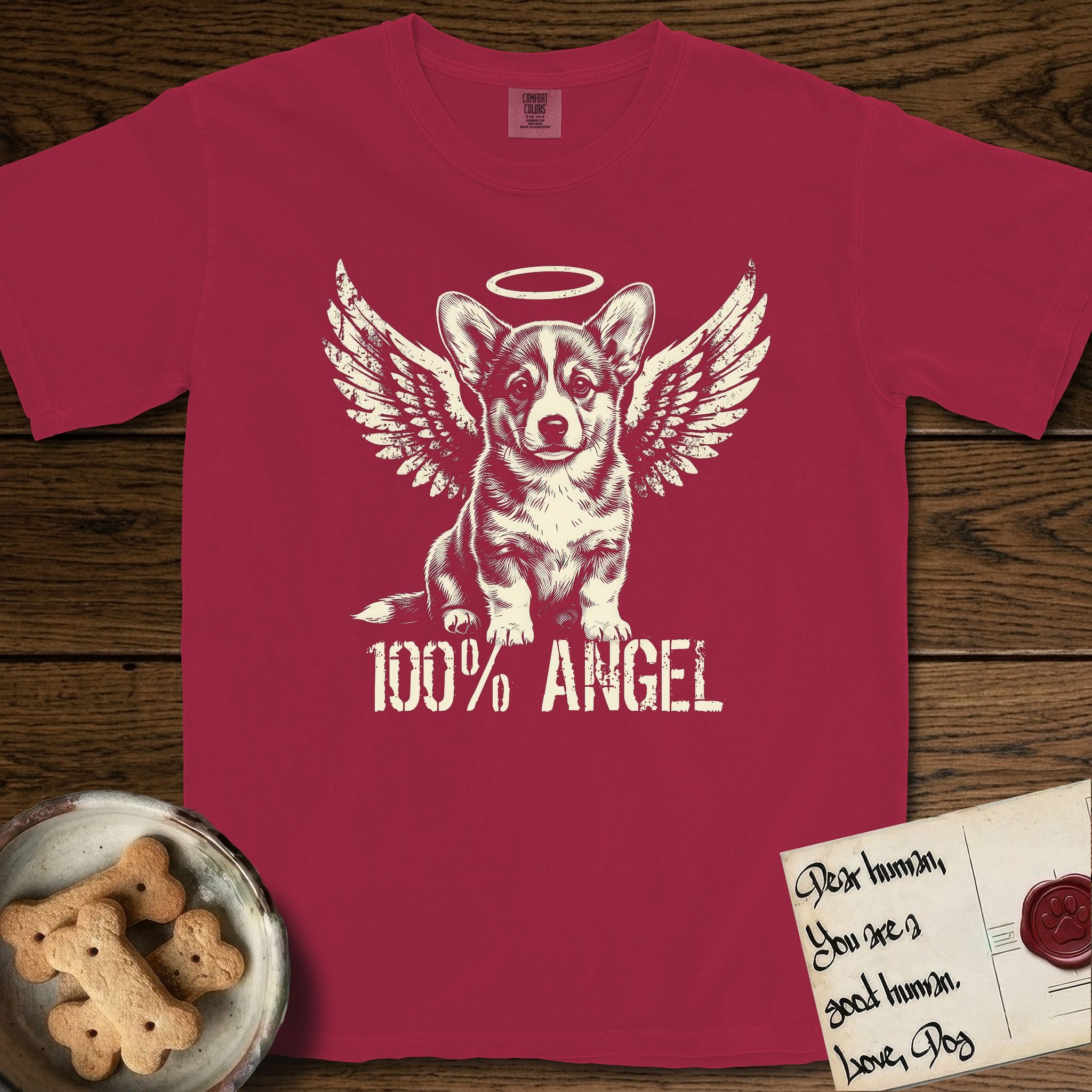 Corgi T-Shirt flat lay in Chili, featuring Distressed cream one-color screen-print of a Pembroke Welsh Corgi puppy as an angel, big erect ears and short legs, wings spread and a halo above, with 100% ANGEL lettering across the bottom.