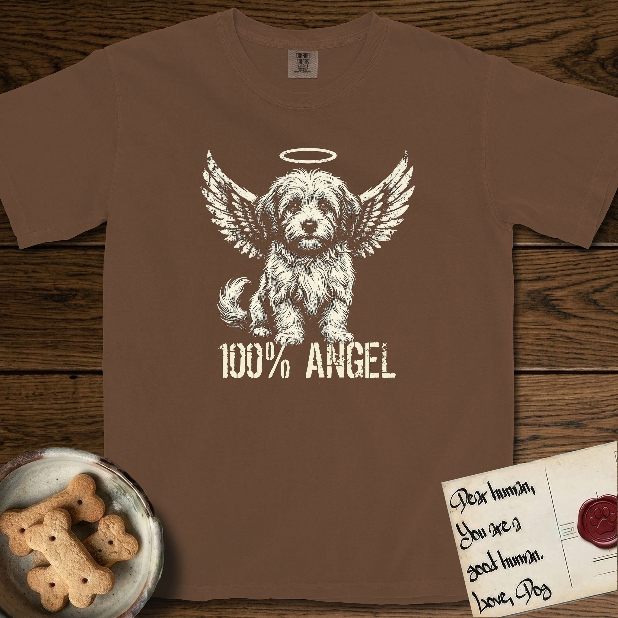 Coton de Tulear T-Shirt flat lay in Espresso, featuring Distressed cream one-color screen-print of a fluffy white Coton de Tulear puppy as an angel, plumed tail curled beside him, wings spread and a halo above, with 100% ANGEL lettering across the bottom.
