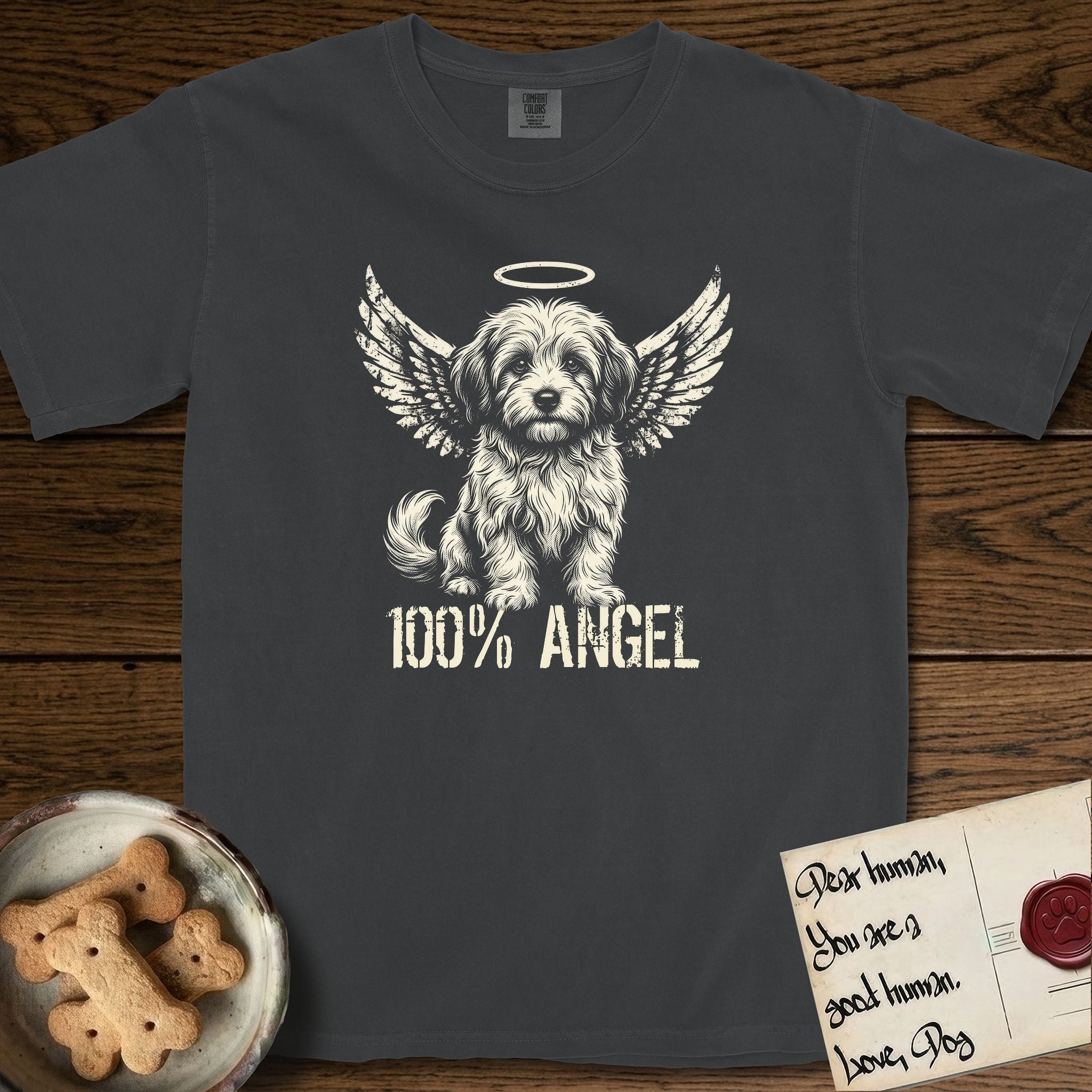 Coton de Tulear T-Shirt flat lay in Graphite, featuring Distressed cream one-color screen-print of a fluffy white Coton de Tulear puppy as an angel, plumed tail curled beside him, wings spread and a halo above, with 100% ANGEL lettering across the bottom.