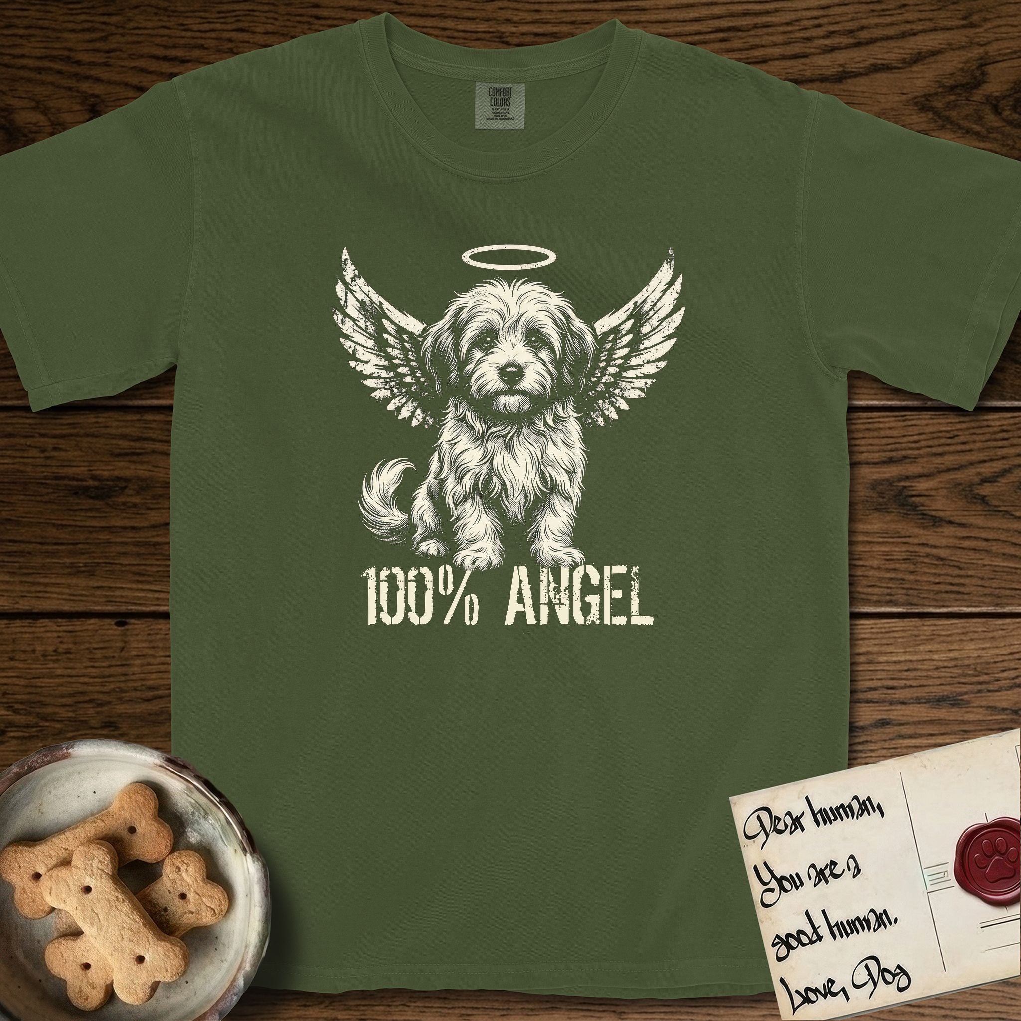 Coton de Tulear T-Shirt flat lay in Hemp, featuring Distressed cream one-color screen-print of a fluffy white Coton de Tulear puppy as an angel, plumed tail curled beside him, wings spread and a halo above, with 100% ANGEL lettering across the bottom.