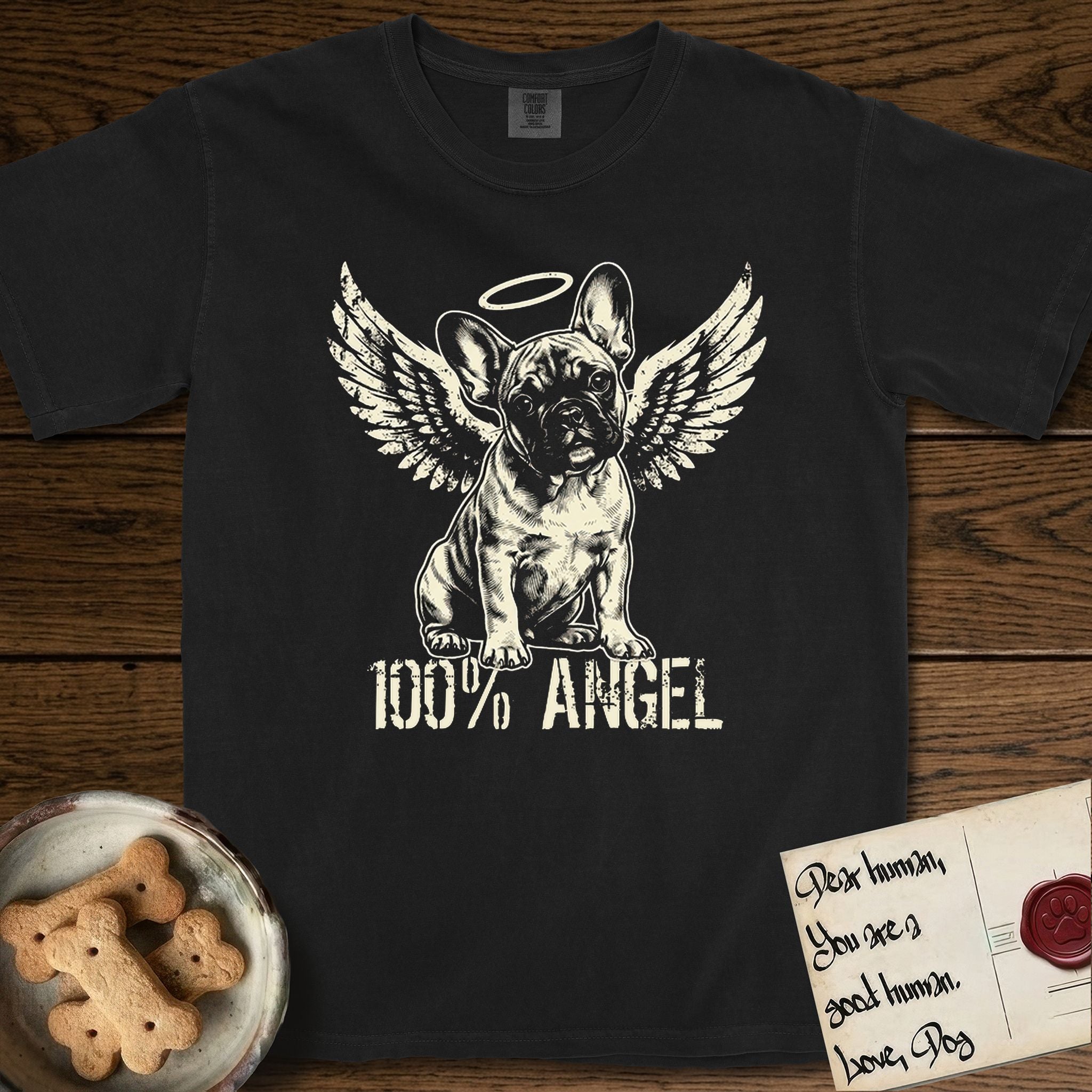 French Bulldog T-Shirt flat lay in Black, featuring Distressed cream one-color screen-print of a French Bulldog puppy as an angel, head cocked to one side, wings spread and a halo above, with 100% ANGEL lettering across the bottom.