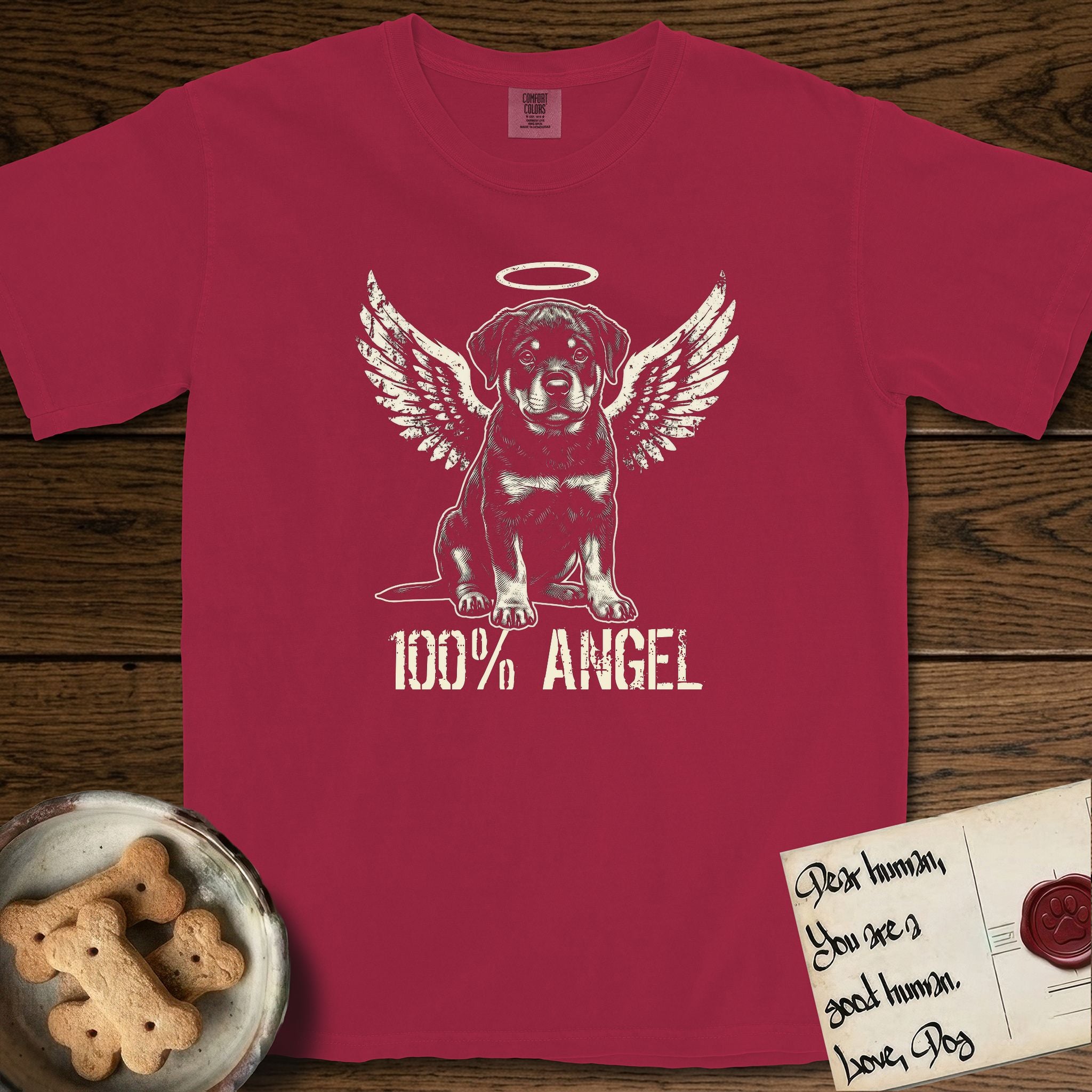 Rottweiler T-Shirt flat lay in Chili, featuring Distressed cream one-color screen-print of a Rottweiler puppy as an angel, sitting square and sturdy, wings spread and a halo above, with 100% ANGEL lettering across the bottom.
