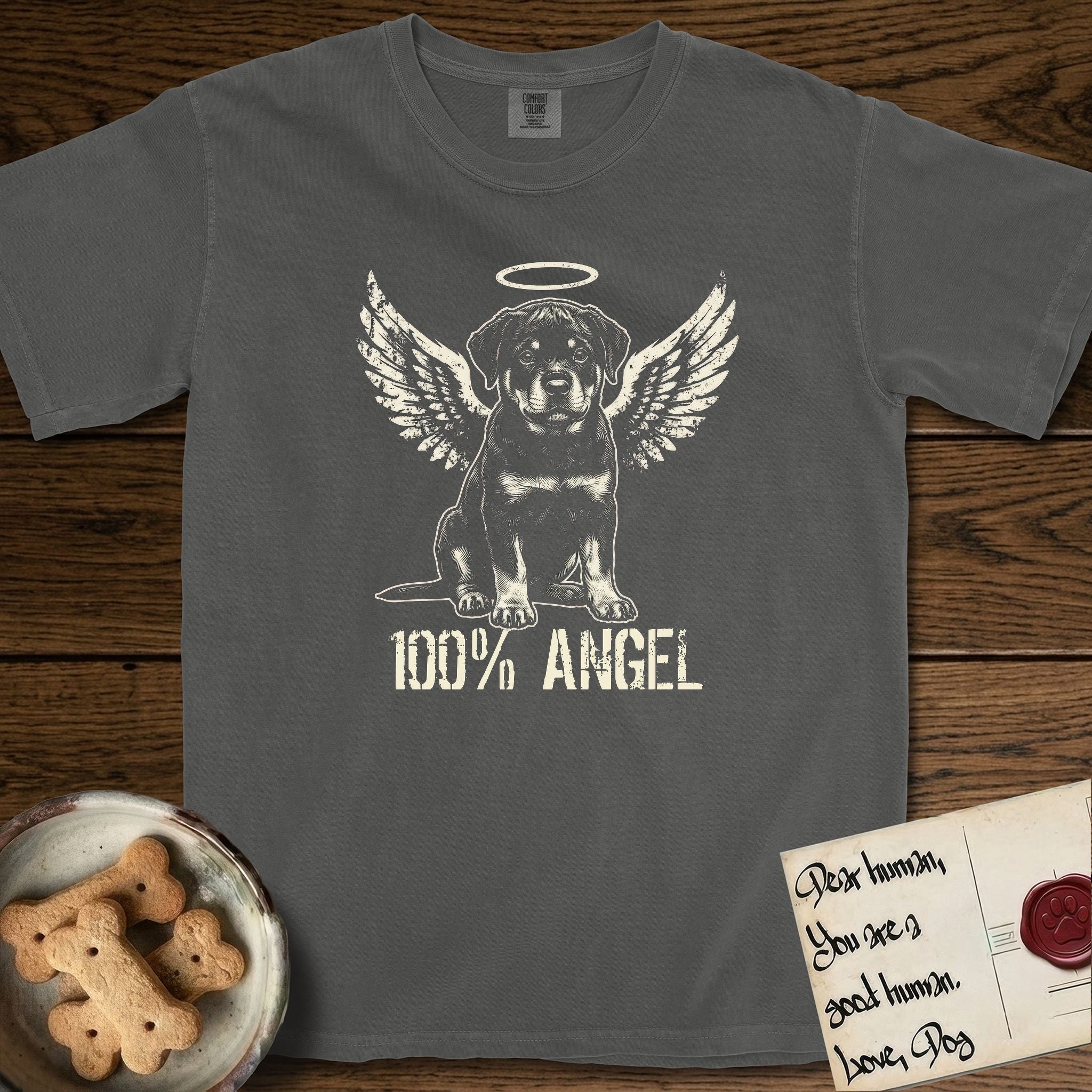 Rottweiler T-Shirt flat lay in Pepper, featuring Distressed cream one-color screen-print of a Rottweiler puppy as an angel, sitting square and sturdy, wings spread and a halo above, with 100% ANGEL lettering across the bottom.