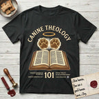 Canine Theology 101 T-Shirt flat lay in Black, featuring a cream badge with an open book and two glowing paw prints rising above it, ringed by a circular halo.