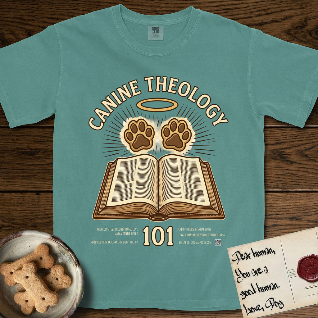 Canine Theology 101 T-Shirt flat lay in Blue Spruce, featuring a cream badge with an open book and two glowing paw prints rising above it, ringed by a circular halo.