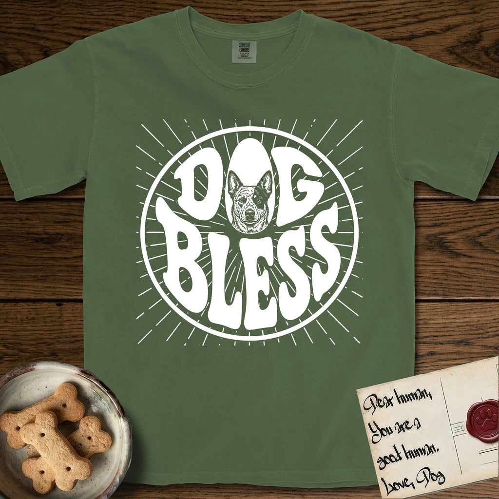 Dog Bless Australian Cattle Dog T-Shirt flat lay in Moss, featuring Retro bubble-letter badge reading DOG BLESS with a speckled Australian Cattle Dog face framed in the letter O, hand-drawn sunburst rays radiating outward.