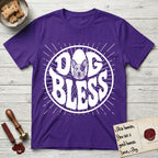 Dog Bless Australian Cattle Dog T-Shirt flat lay in Purple, featuring Retro bubble-letter badge reading DOG BLESS with a speckled Australian Cattle Dog face framed in the letter O, hand-drawn sunburst rays radiating outward.
