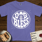 Dog Bless Beagle T-Shirt flat lay in Violet, featuring Retro bubble-letter badge reading DOG BLESS with a gentle Beagle face framed in the letter O, hand-drawn sunburst rays radiating outward.