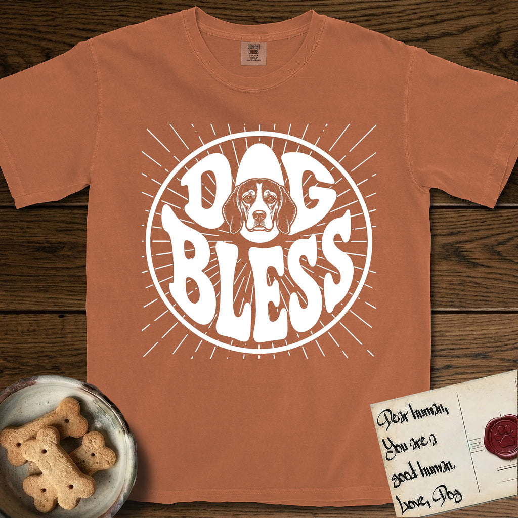 Dog Bless Beagle T-Shirt flat lay in Yam, featuring Retro bubble-letter badge reading DOG BLESS with a gentle Beagle face framed in the letter O, hand-drawn sunburst rays radiating outward.