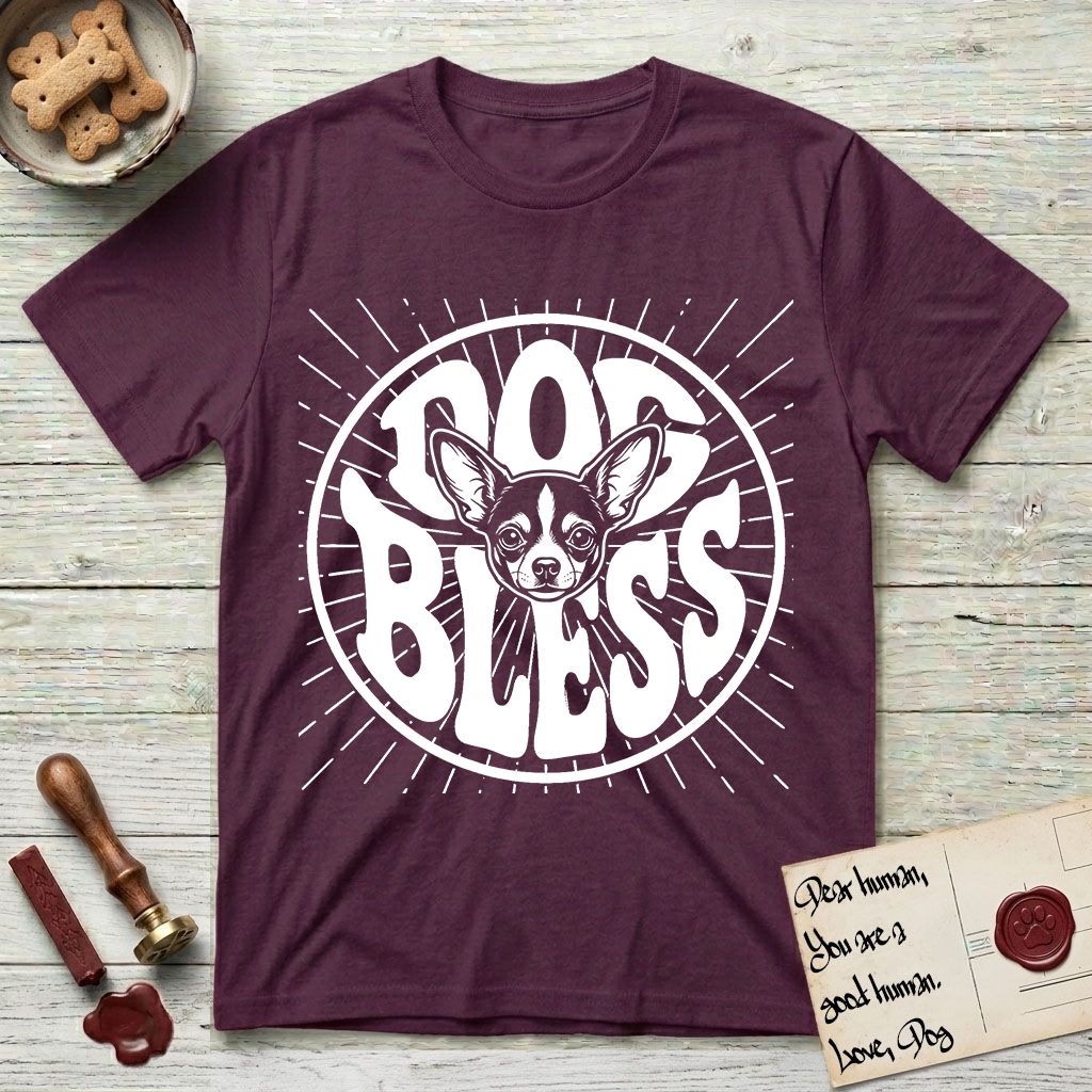 Dog Bless Chihuahua T-Shirt flat lay in Maroon, featuring Retro bubble-letter badge reading DOG BLESS with a wide-eyed Chihuahua face framed in the letter O, oversized ears reaching past the letter, hand-drawn sunburst rays radiating outward.