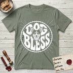 Dog Bless Corgi T-Shirt flat lay in Sage, featuring Retro bubble-letter badge reading DOG BLESS with a smiling Corgi face framed in the letter O, chest fluff spilling below the letter, hand-drawn sunburst rays radiating outward.