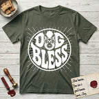 Dog Bless German Shepherd T-Shirt flat lay in Heather Military Green, featuring Retro bubble-letter badge reading DOG BLESS with a German Shepherd face with tall upright ears framed in the letter O, hand-drawn sunburst rays radiating outward.
