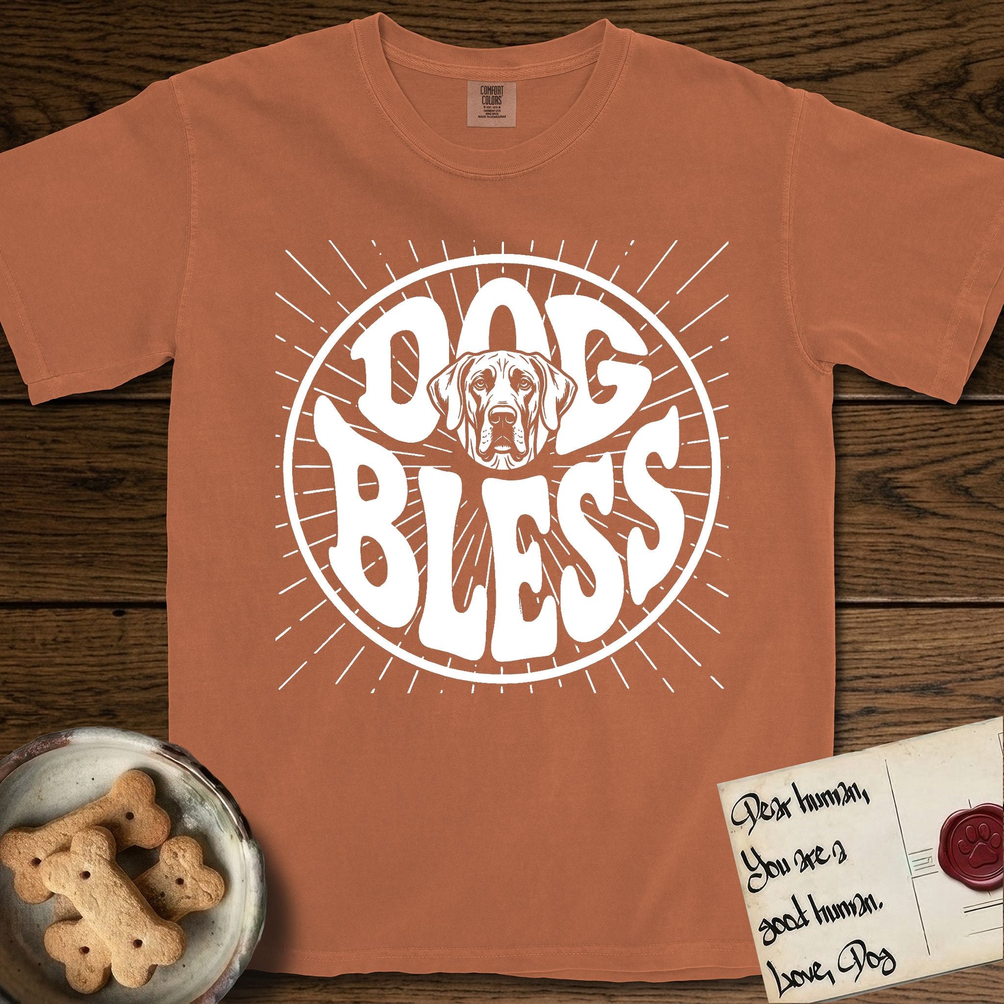 Dog Bless Great Dane T-Shirt flat lay in Yam, featuring Retro bubble-letter badge reading DOG BLESS with a gentle Great Dane face with natural floppy ears framed in the letter O, hand-drawn sunburst rays radiating outward.