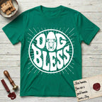 Dog Bless Greyhound T-Shirt flat lay in Kelly Green, featuring Retro bubble-letter badge reading DOG BLESS with a slender Greyhound face with folded rose ears framed in the letter O, hand-drawn sunburst rays radiating outward.