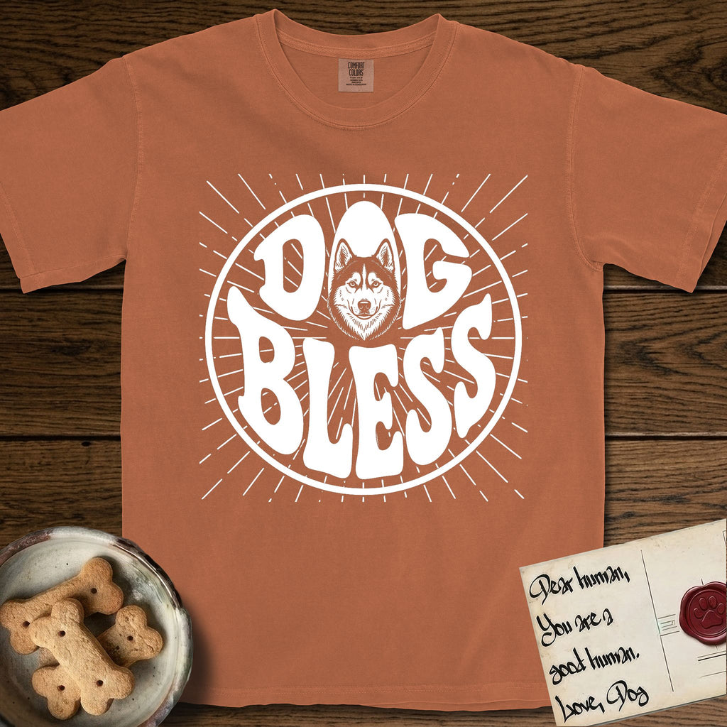 Dog Bless Husky T-Shirt flat lay in Yam, featuring Retro bubble-letter badge reading DOG BLESS with a masked Husky face framed in the letter O, hand-drawn sunburst rays radiating outward.