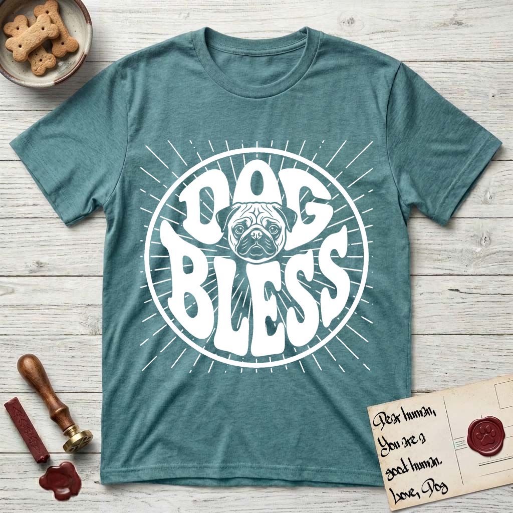 Dog Bless Pug T-Shirt flat lay in Heather Galapagos Blue, featuring Retro bubble-letter badge reading DOG BLESS with a wrinkled Pug face with large round eyes framed in the letter O, hand-drawn sunburst rays radiating outward.