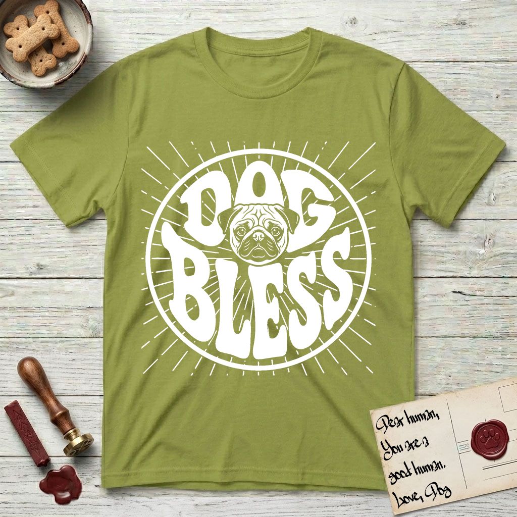 Dog Bless Pug T-Shirt flat lay in Kiwi, featuring Retro bubble-letter badge reading DOG BLESS with a wrinkled Pug face with large round eyes framed in the letter O, hand-drawn sunburst rays radiating outward.