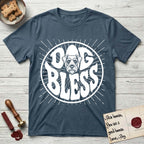 Dog Bless Schnauzer T-Shirt flat lay in Indigo Blue, featuring Retro bubble-letter badge reading DOG BLESS with a bearded Schnauzer face with bushy eyebrows framed in the letter O, hand-drawn sunburst rays radiating outward.