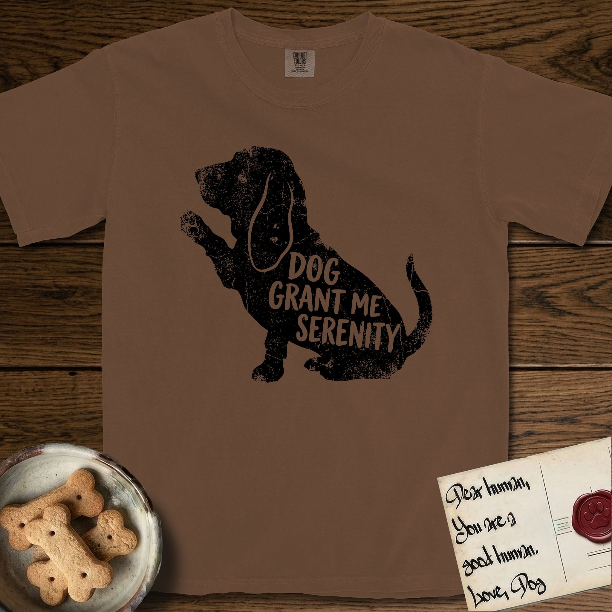 Serenity Basset Hound T-Shirt flat lay in Espresso, featuring Distressed black screen print silhouette of a Basset Hound sitting in profile with one paw raised and long ears hanging, the words DOG GRANT ME SERENITY showing through his body in the shirt color.