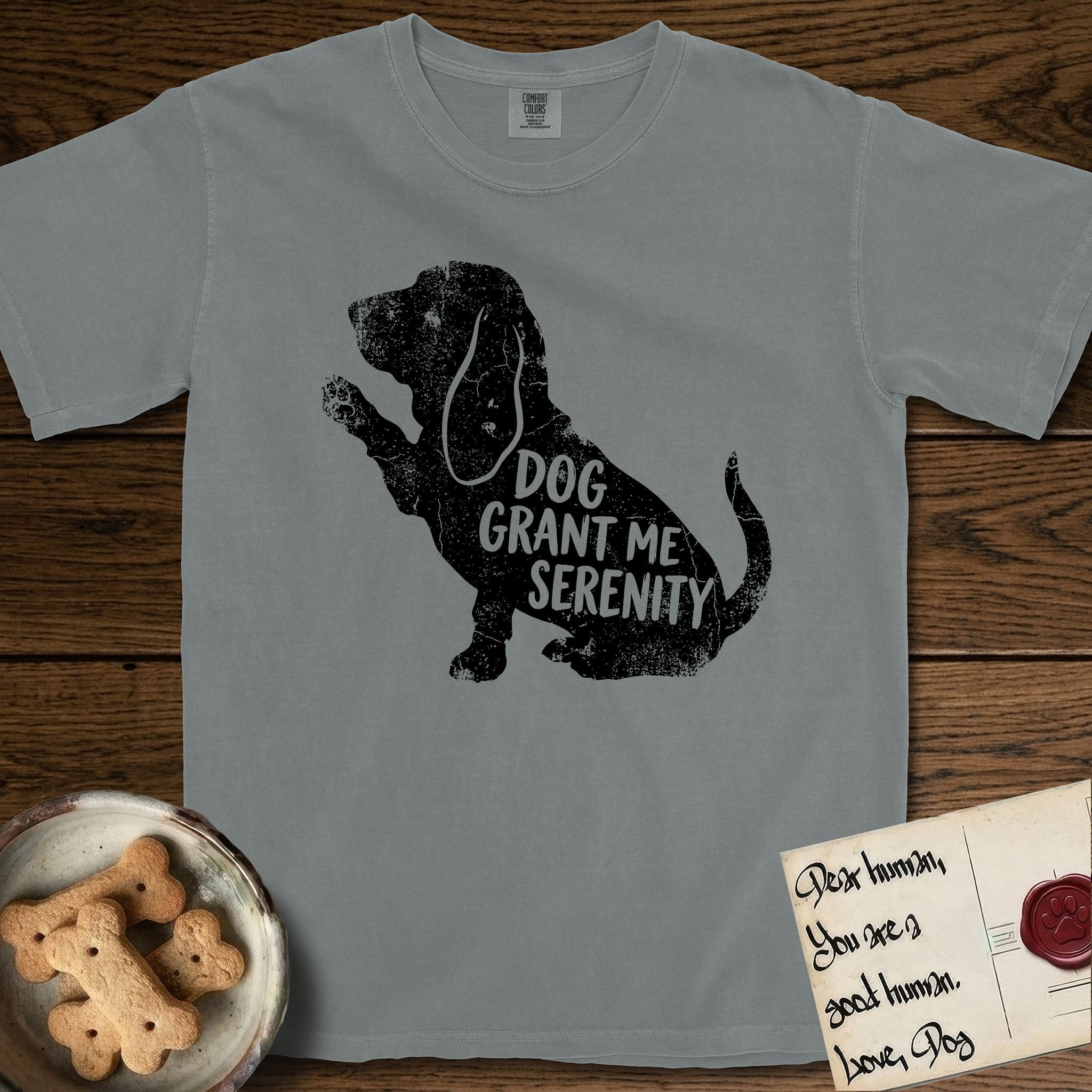 Serenity Basset Hound T-Shirt flat lay in Granite, featuring Distressed black screen print silhouette of a Basset Hound sitting in profile with one paw raised and long ears hanging, the words DOG GRANT ME SERENITY showing through his body in the shirt color.