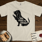 Serenity Basset Hound T-Shirt flat lay in Ivory, featuring Distressed black screen print silhouette of a Basset Hound sitting in profile with one paw raised and long ears hanging, the words DOG GRANT ME SERENITY showing through his body in the shirt color.