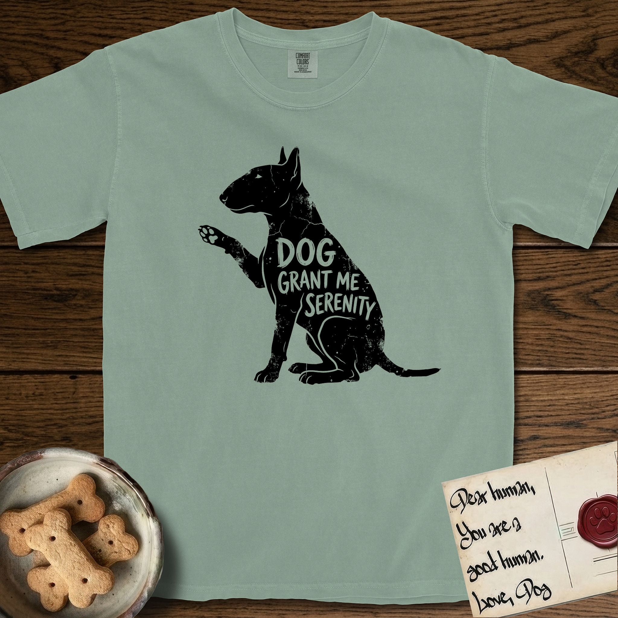 Serenity Bull Terrier T-Shirt flat lay in Bay, featuring Distressed black screen print silhouette of a Bull Terrier sitting in profile with one paw raised and an egg-shaped head, the words DOG GRANT ME SERENITY showing through her body in the shirt color.