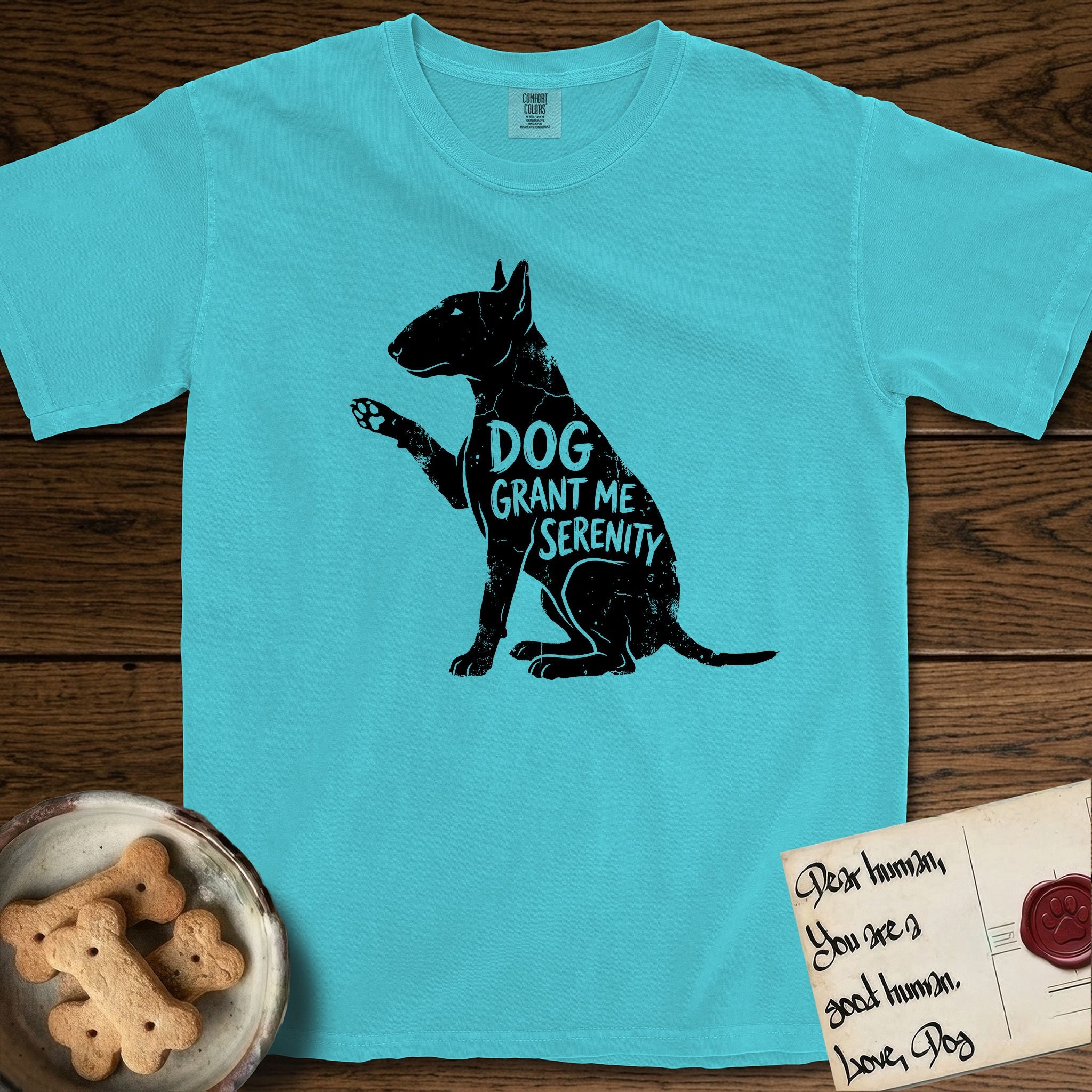 Serenity Bull Terrier T-Shirt flat lay in Lagoon Blue, featuring Distressed black screen print silhouette of a Bull Terrier sitting in profile with one paw raised and an egg-shaped head, the words DOG GRANT ME SERENITY showing through her body in the shirt color.