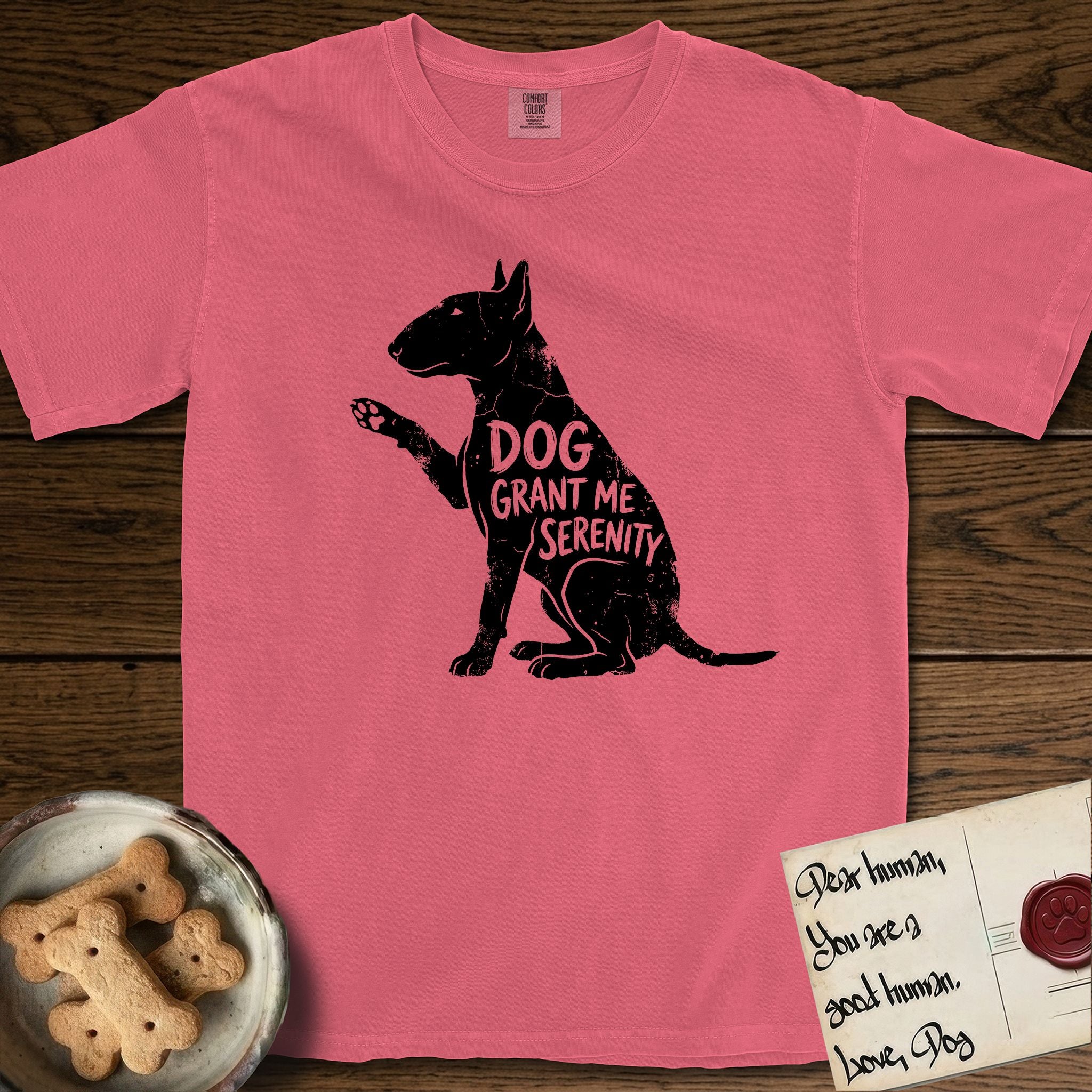 Serenity Bull Terrier T-Shirt flat lay in Watermelon, featuring Distressed black screen print silhouette of a Bull Terrier sitting in profile with one paw raised and an egg-shaped head, the words DOG GRANT ME SERENITY showing through her body in the shirt color.