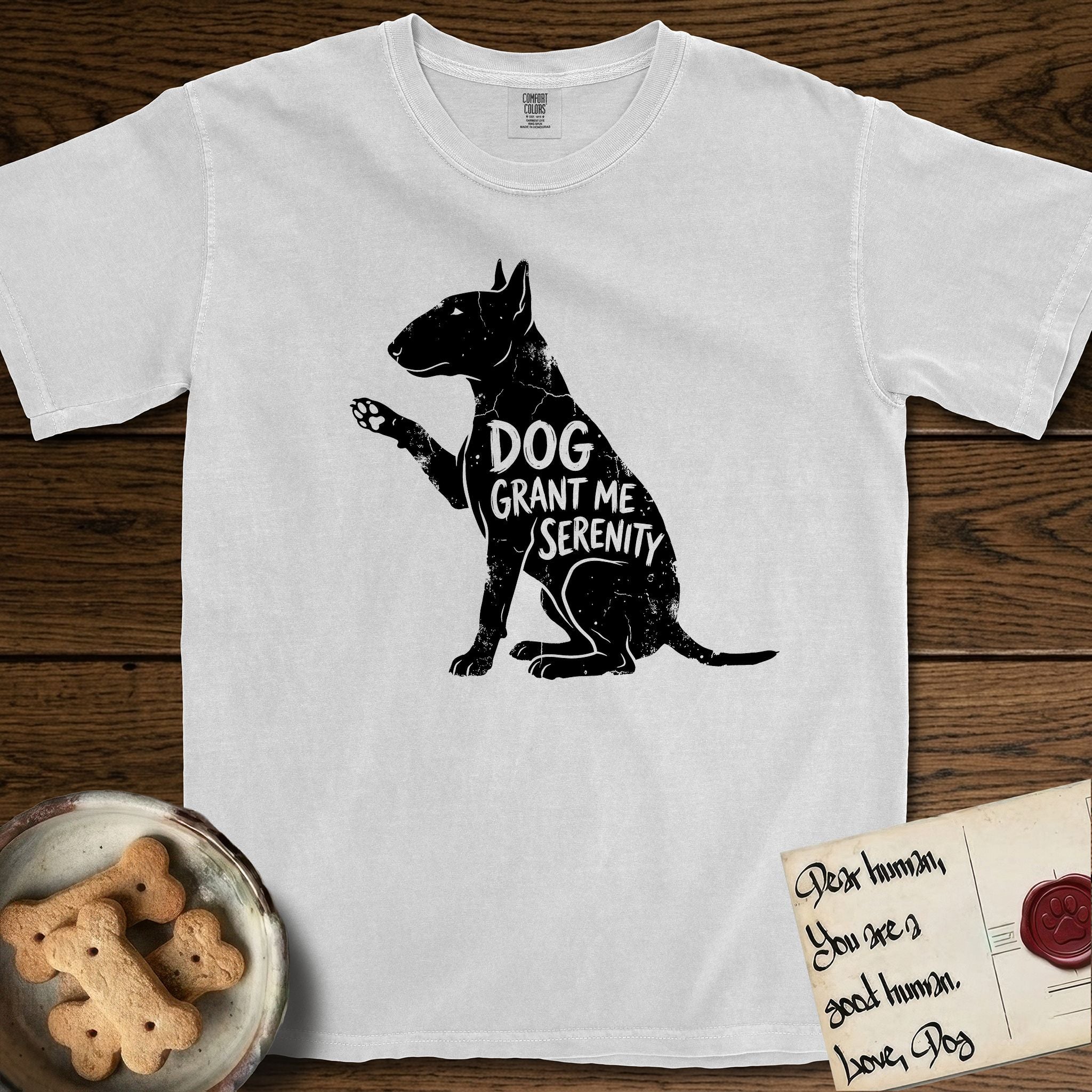 Serenity Bull Terrier T-Shirt flat lay in White, featuring Distressed black screen print silhouette of a Bull Terrier sitting in profile with one paw raised and an egg-shaped head, the words DOG GRANT ME SERENITY showing through her body in the shirt color.