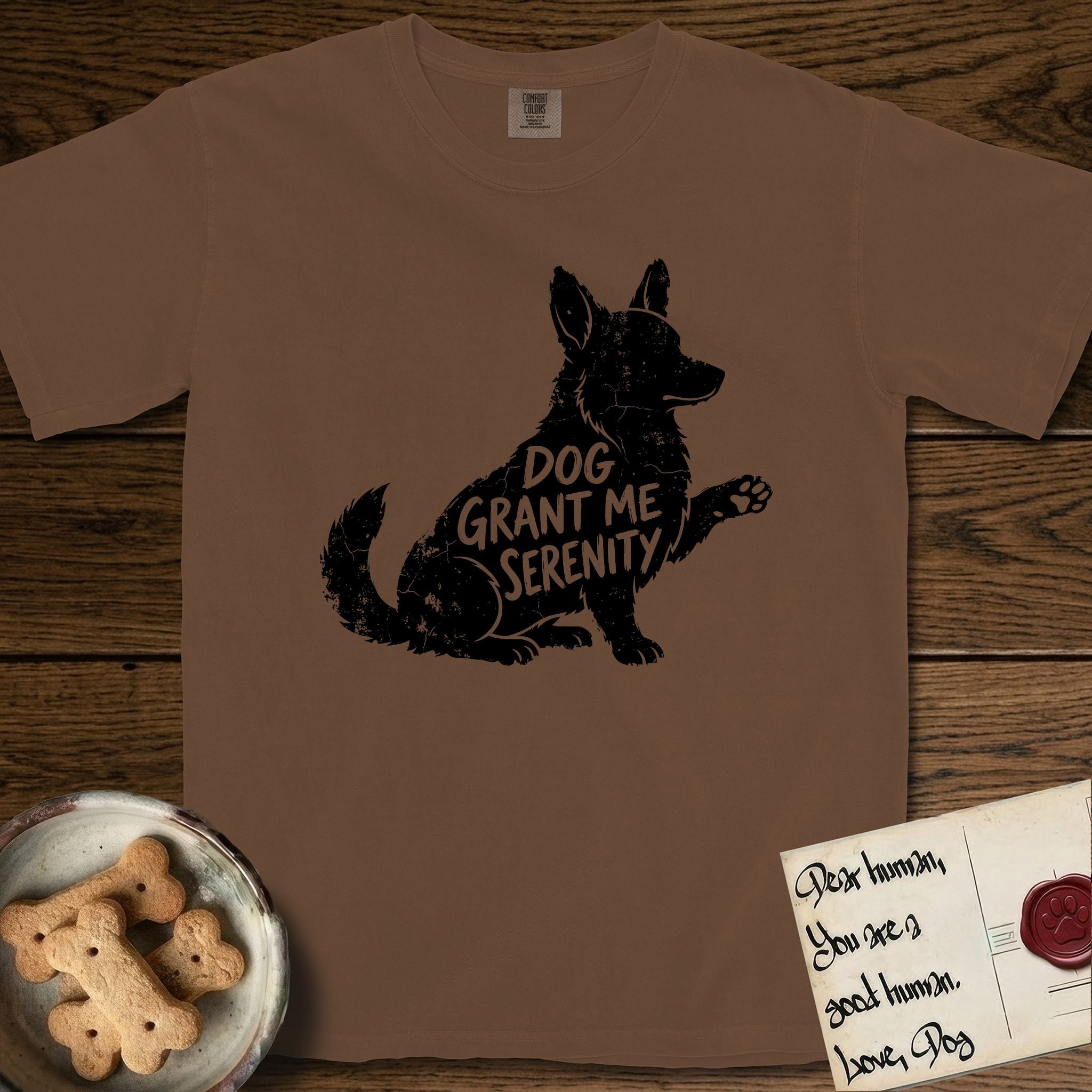 Serenity Corgi T-Shirt flat lay in Espresso, featuring Distressed black screen print silhouette of a Corgi sitting in profile with one paw raised, upright ears and a full brush tail, the words DOG GRANT ME SERENITY showing through his body in the shirt color.