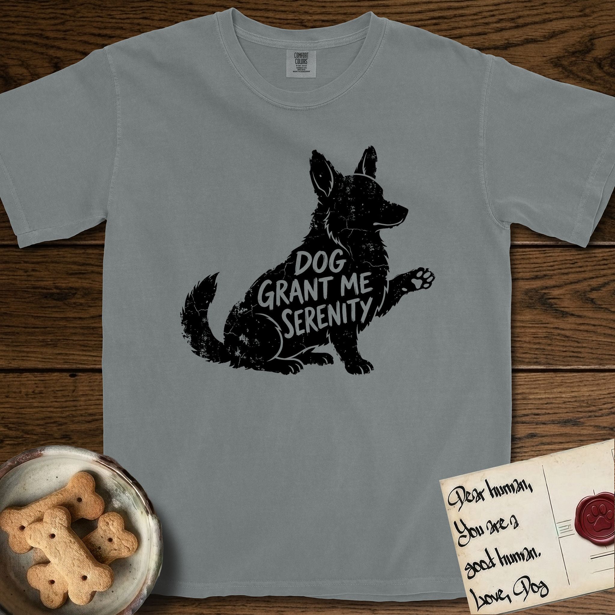 Serenity Corgi T-Shirt flat lay in Granite, featuring Distressed black screen print silhouette of a Corgi sitting in profile with one paw raised, upright ears and a full brush tail, the words DOG GRANT ME SERENITY showing through his body in the shirt color.