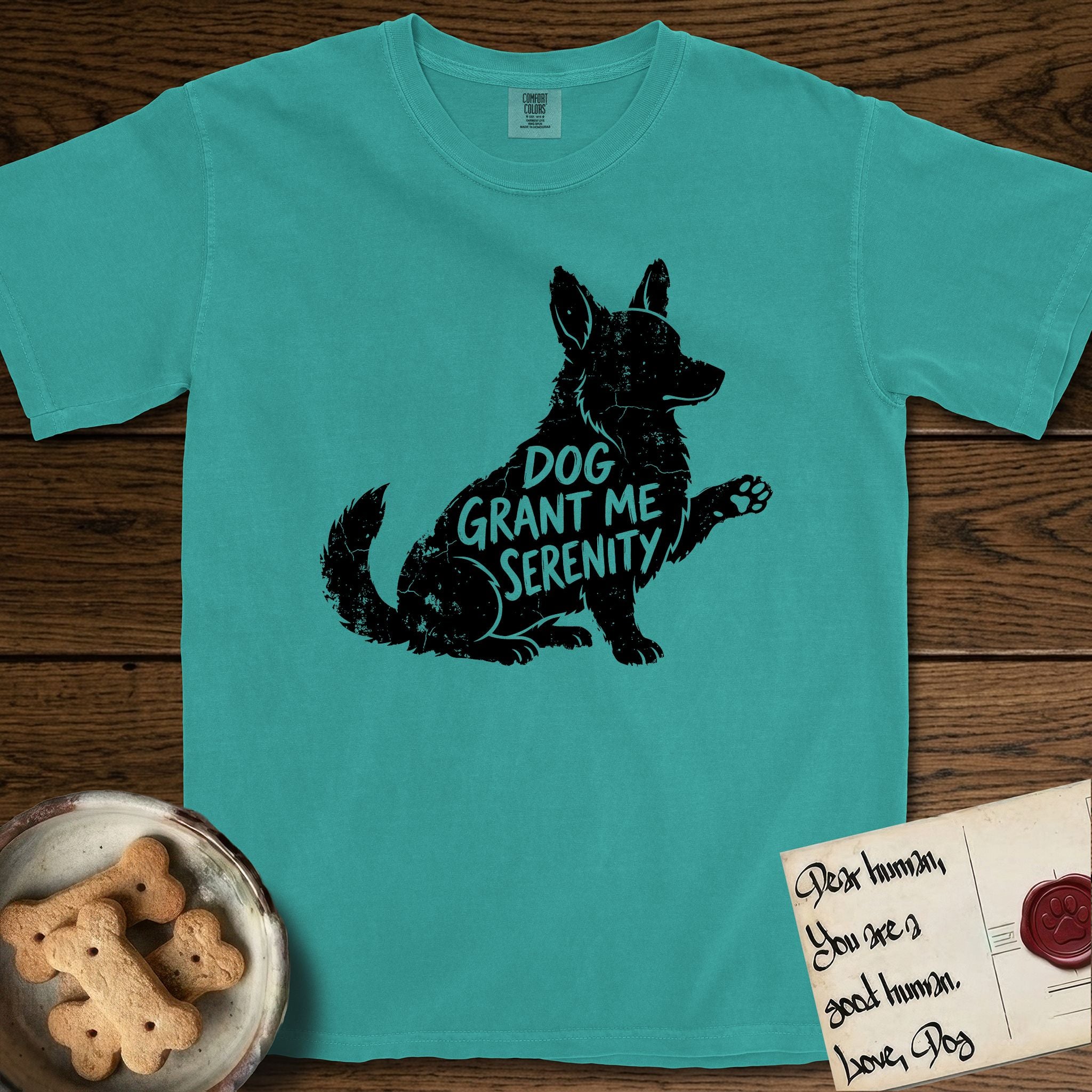 Serenity Corgi T-Shirt flat lay in Seafoam, featuring Distressed black screen print silhouette of a Corgi sitting in profile with one paw raised, upright ears and a full brush tail, the words DOG GRANT ME SERENITY showing through his body in the shirt color.