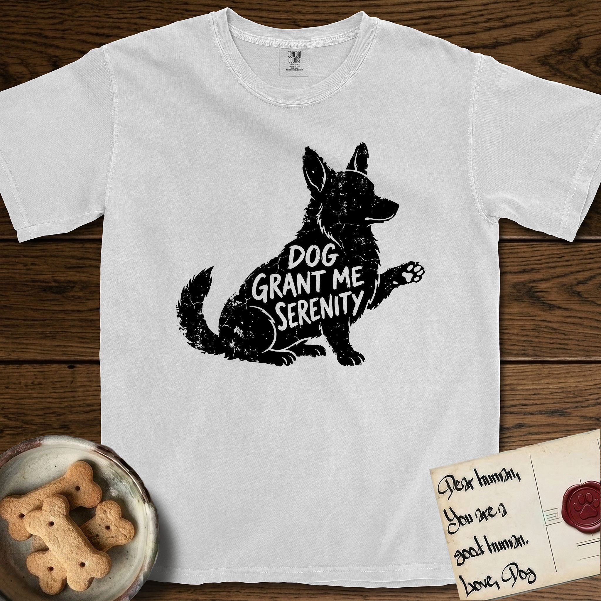 Serenity Corgi T-Shirt flat lay in White, featuring Distressed black screen print silhouette of a Corgi sitting in profile with one paw raised, upright ears and a full brush tail, the words DOG GRANT ME SERENITY showing through his body in the shirt color.